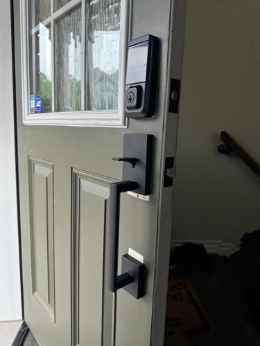 Electronic smart deadbolt and modern black handle installed on front entry door for secure access.