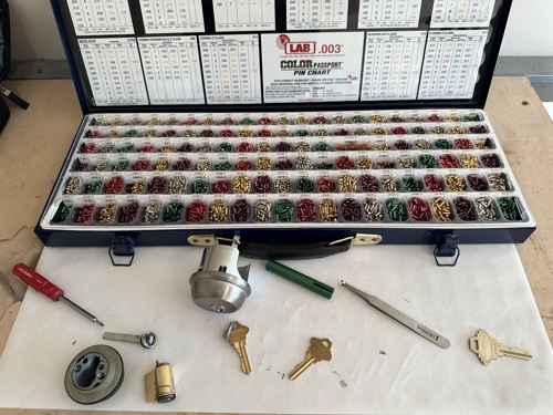 Locksmith rekeying kit with colored pins, lock cylinder, keys, and tools for professional service.